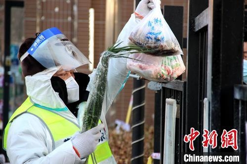 工作人员为管控区内居民传递生活物资。　王景巍 摄